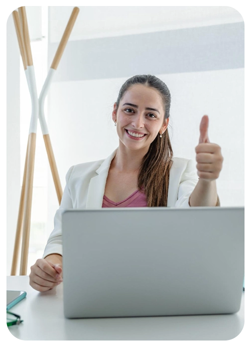 Mujer sonriendo frente a su ordenador y haciendo gesto de aprobación, reflejando la satisfacción con formaciones de confianza